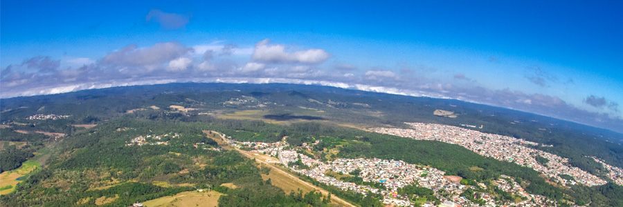 Foto aérea da Area de Proteção Ambiental Bororé Colônia com o horizonte curvado pela lente da camera. Do lado direito da metade para baixo, observa-se uma região urbana. Do lado esquerdo é a parte verde da área com pequenas partes sem vegetação.